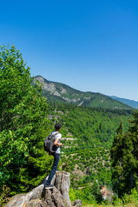 A young man stands on the edge of a cliff overlooking the mountains. summer hiking in the mountains.