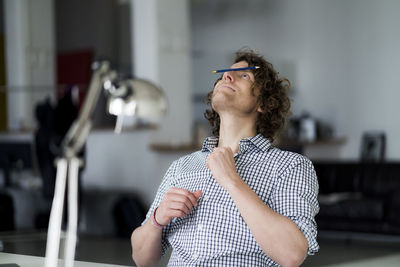 Businessman balancing pencil on his face