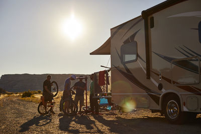 A group of guys working on mountain bikes at the rear of an rv.