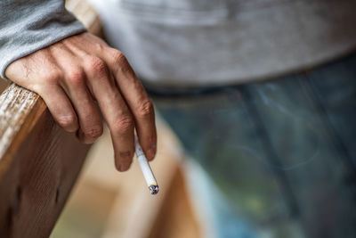 Midsection of man holding cigarette