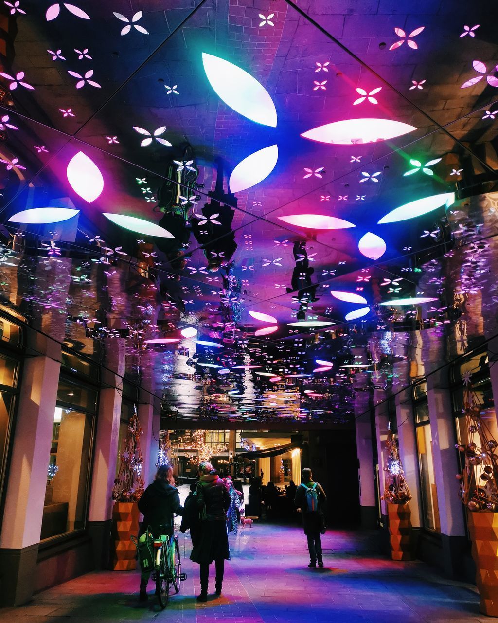 PEOPLE WALKING ON ILLUMINATED STREET AT NIGHT