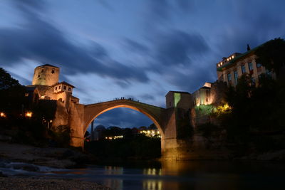 Low angle view of bridge over river against cloudy sky