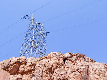 Low angle view of electricity pylon against clear sky