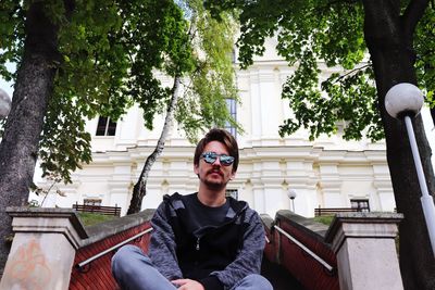 Portrait of man wearing sunglasses while sitting on steps