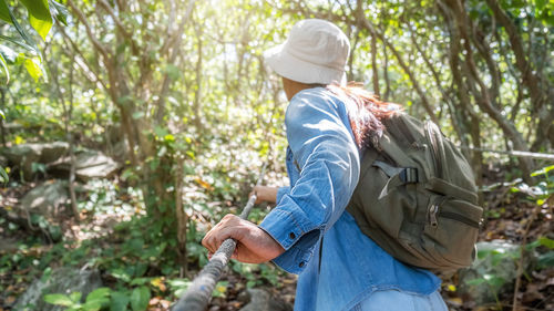 Side view of woman standing against trees