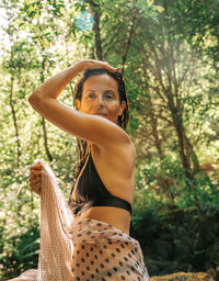 Young woman standing against trees