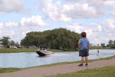 Rear view of boy on shore against sky