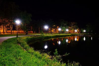 Illuminated street by lake at night