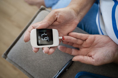 Hands of woman using glucometer at home