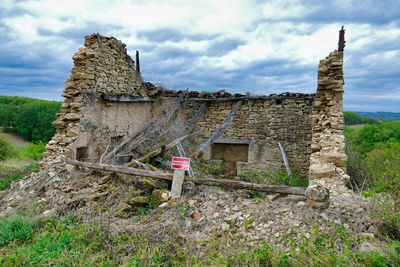 Old ruins of building on field against sky