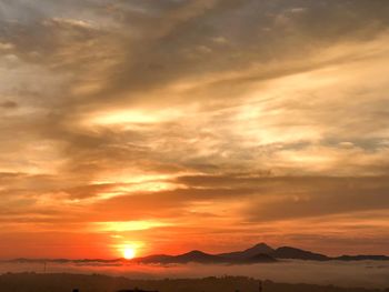 Scenic view of dramatic sky over silhouette mountains during sunset