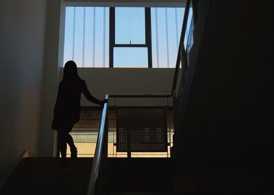 Rear view of silhouette woman standing on staircase