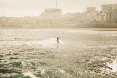 Man wearing santa costume surfing on sea against sky