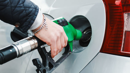 Hand of a gas station man is putting gasoline into a car