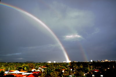 Rainbow over city against sky
