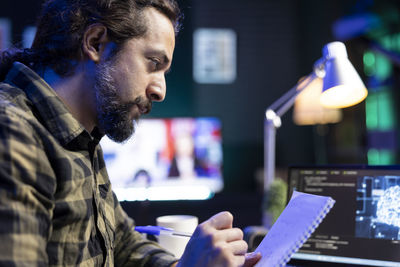 Side view of man using mobile phone while sitting at home