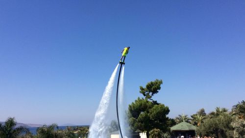 Low angle view of flags against clear blue sky