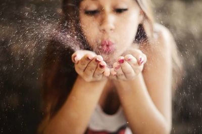 Close-up of young woman blowing powder