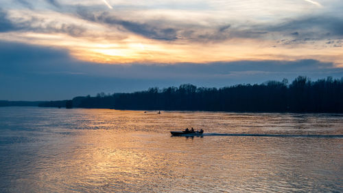 Silhouette boat in calm sea at sunset