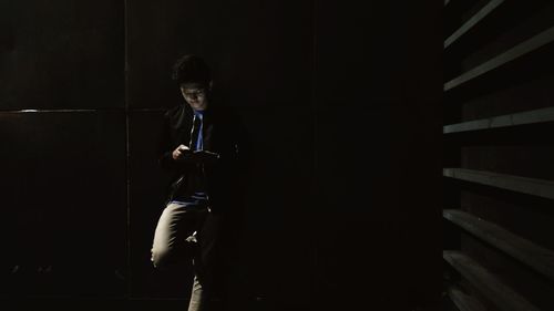 Full length of boy standing in dark room