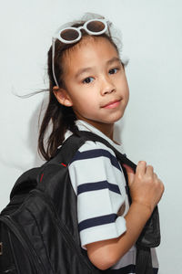Portrait of young woman standing against wall