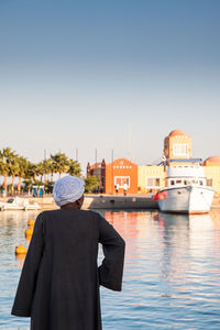 Rear view of man on boat in canal against buildings