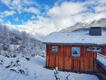 House on snow covered mountain against sky