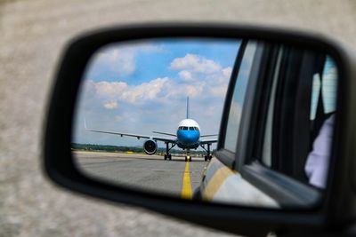 Reflection of airplane seen on side-view mirror in car