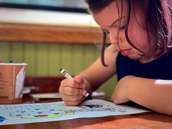 Girl drawing in paper on table at home