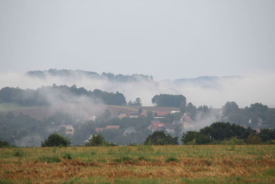 Houses in village against clear sky during foggy weather