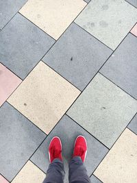 Low section of person wearing red shoes on footpath