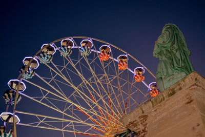 Low angle view of ferris wheel against clear blue sky