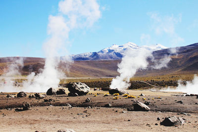 Smoke emitting from volcanic landscape against sky