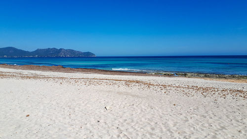 Scenic view of beach against clear blue sky