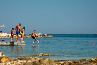 People on beach against clear sky