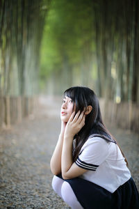 Side view of young woman crouching in bamboo groove