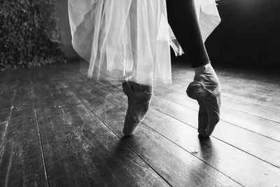 Low section of female ballet dancer dancing on hardwood floor
