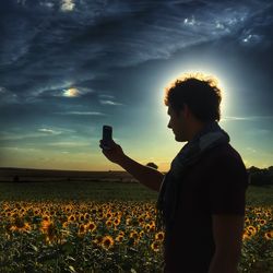 Man using mobile phone against sky during sunset