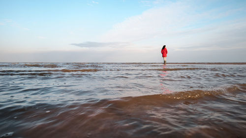 Woman standing on beach against sky