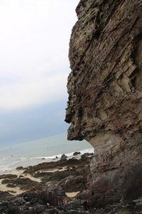 Close-up of cliff by sea against sky