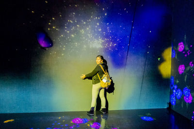 Woman standing against illuminated lights at night