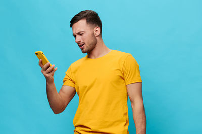 Young man using mobile phone against blue background