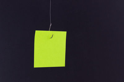 Close-up of yellow paper hanging against black background