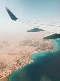 Aerial view of airplane flying over sea against sky