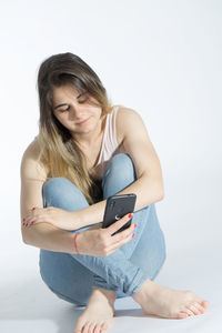 Young woman using smart phone against white background