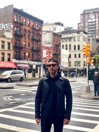 Portrait of young man standing on road in city