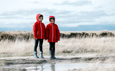 Full length portrait of friends standing on shore against sky