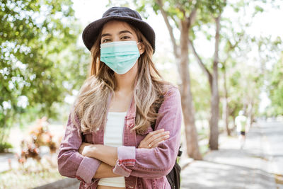 Portrait of young woman standing against tree