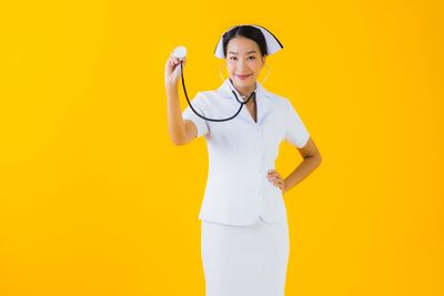 Portrait of woman standing against yellow background