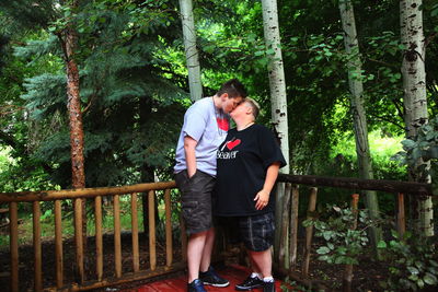 Lesbian couple kissing by wooden fence in backyard